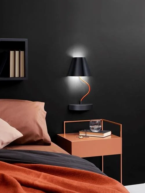 Abajur de parede, design moderno, com cúpula preta e braço flexível laranja, iluminando um quarto de decoração inovadora.