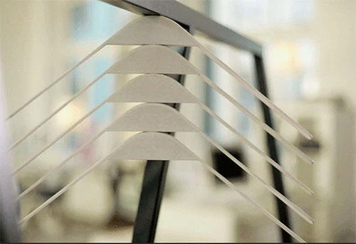 Cabides magnéticos brancos com design angular, cinco unidades empilhadas em barra vertical escura.