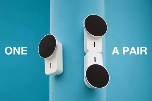 Caixa de som magnética, base branca, disco preto. Uma unidade e um par empilhado fixos em superfície azul.