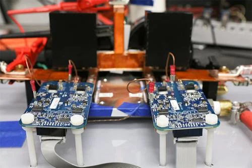 Duas placas de circuito azuis com componentes eletrônicos, alinhadas. Módulos de carregador sem fio magnético para carros elétricos.