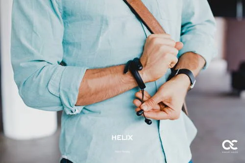 Fone de ouvido Helix preto tipo pulseira sendo ajustado no pulso de um homem de camisa azul.