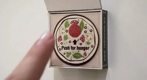 Ímã de geladeira redondo com design de pizza e Push for hunger, em caixa aberta, um dedo o toca. Ótimo para pedido de pizza.