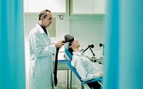 Ondas magnéticas no tratamento de enxaqueca: médico aplicando dispositivo em paciente na clínica.