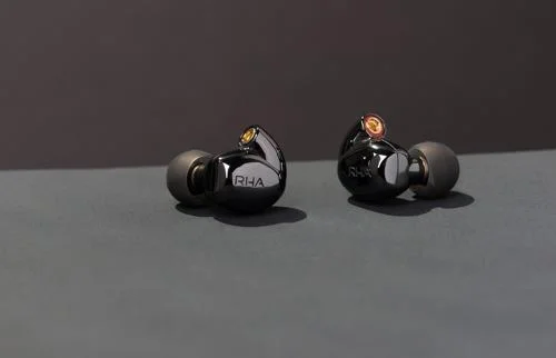 Primeiro fone de ouvido planar magnético sem fio do mundo, RHA. Dois fones intra-auriculares cinza-escuros com detalhes dourados, alinhados.