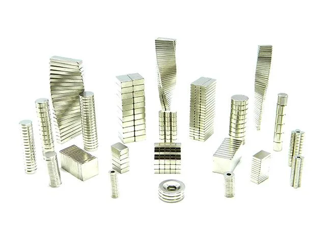 Ímãs de neodímio em vários formatos: blocos retangulares, cilindros e anel prateados, empilhados e dispostos diversamente.
