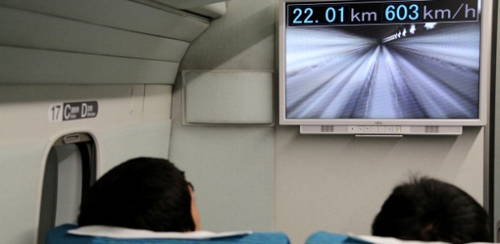 passageiros viajam em trem bala maglev japones enquanto monitor exibe a velocidade alcancada